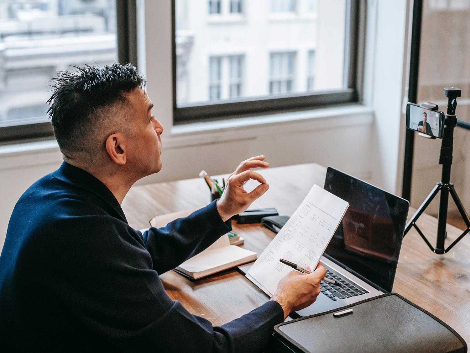 Lawyer sitting at his desk while making a video with his smartphone